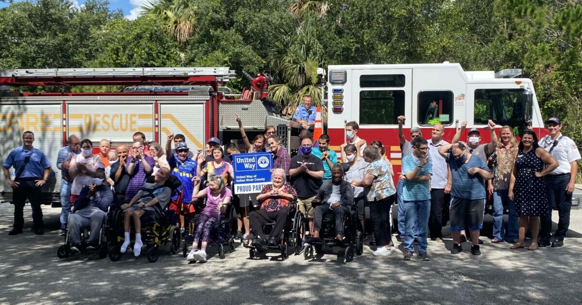 Funded Partner Arc Poses With Their Clients In Front Of A Fire Truck