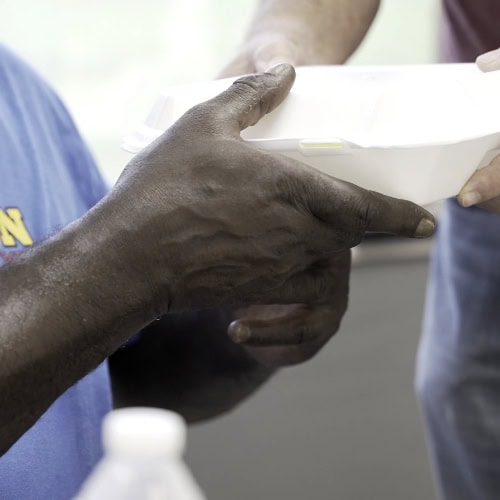Man Handing A Meal To Someone In Need